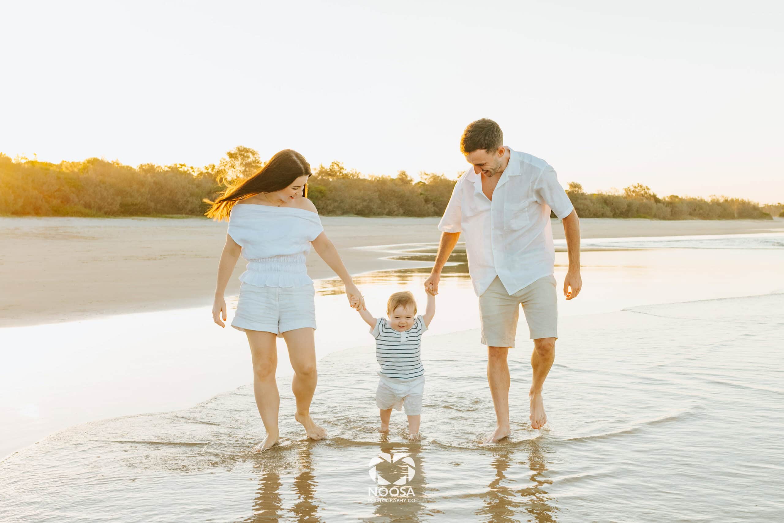 Noosa family photographer capturing a family walking on the beach at golden hour