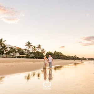 Husband and Wife walking along Noosa Main Beach at sunset